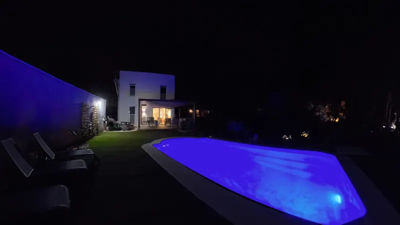 Piscina iluminada y jardín por la noche